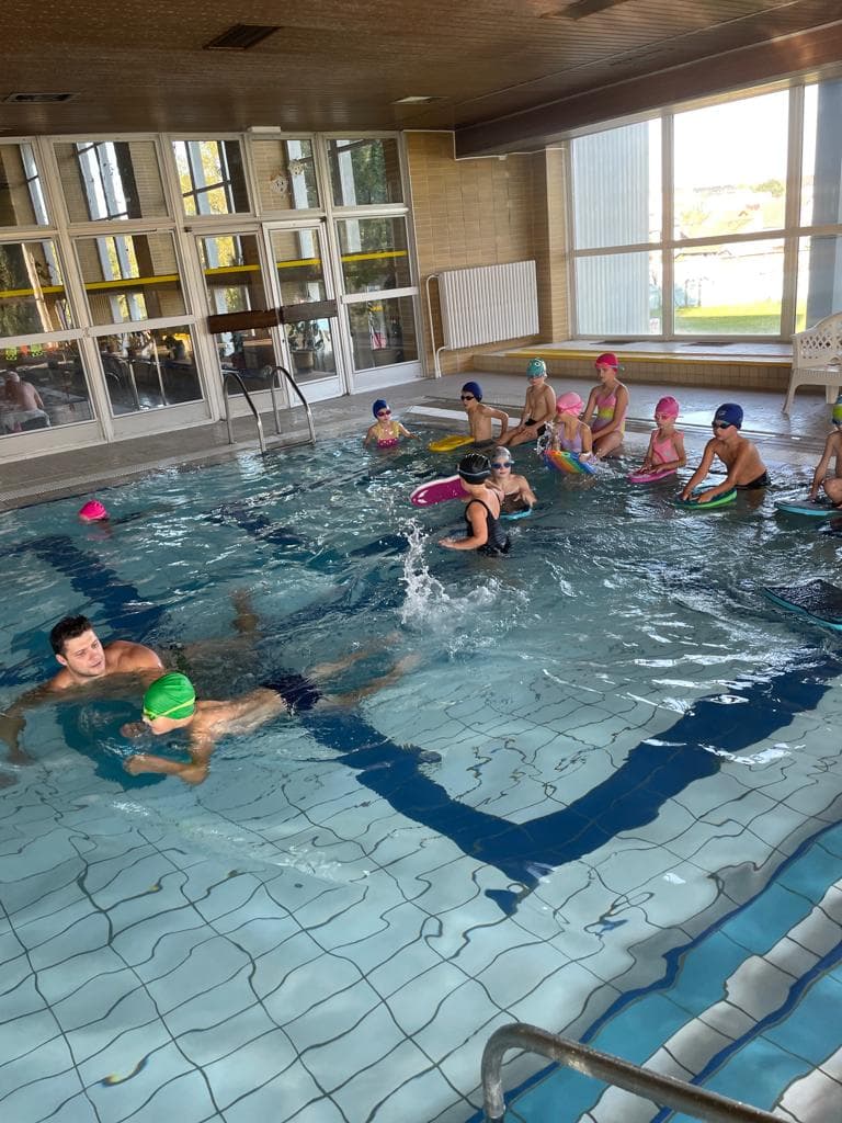 Výuka plávania v krytej plavárni s trénerom a deťmi