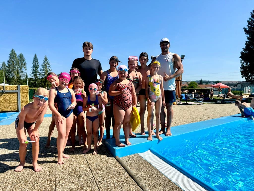 Deti a tréneri na okraji bazéna – skupinová fotografia