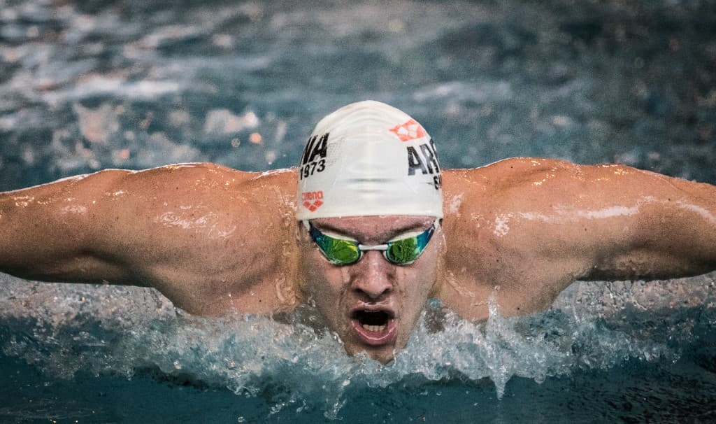 Plavec v motýliku s čiapkou pri výdychu nad hladinou